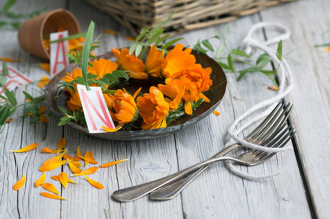 Kranz aus Ringelblumen (Calendula), Blüten auf Teller mit Buchstaben