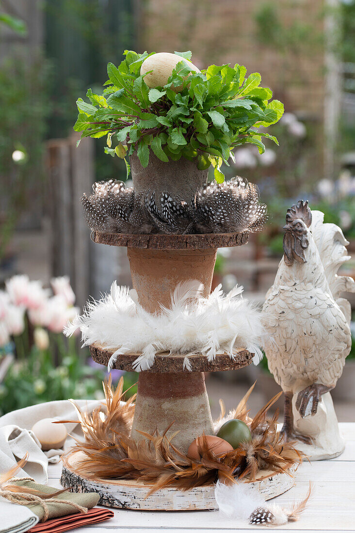 Self-made cake stands with feather wreaths; wooden discs; clay pots; eggs and radish in a pot