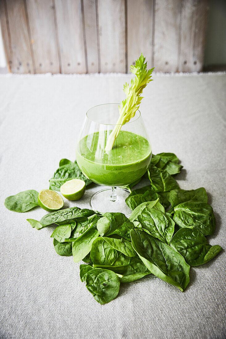Spinach smoothie in a glass with celery
