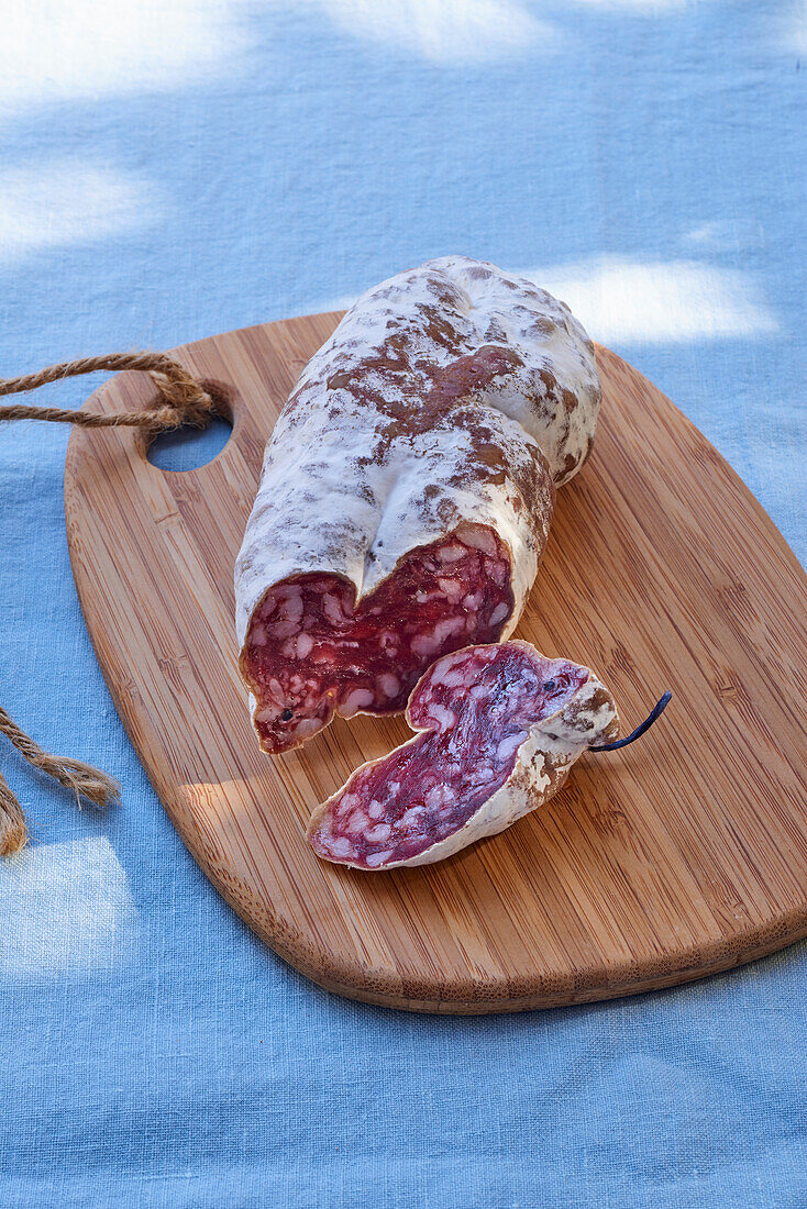 Ein Stück Salami auf Holzbrett