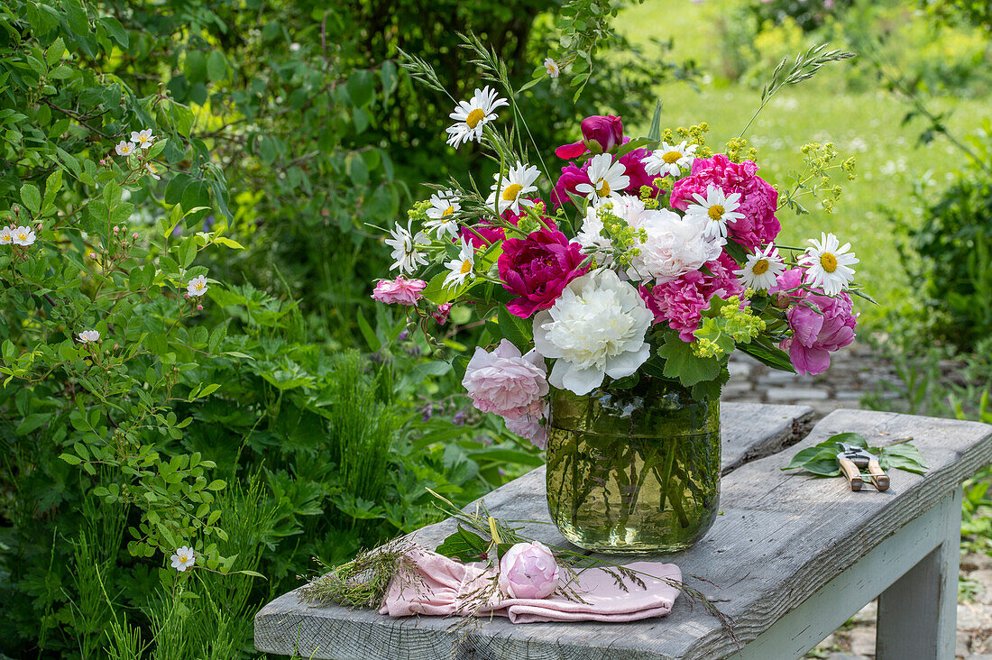 Summer bouquet of peonies, daisies and lady's mantle in a glass vase