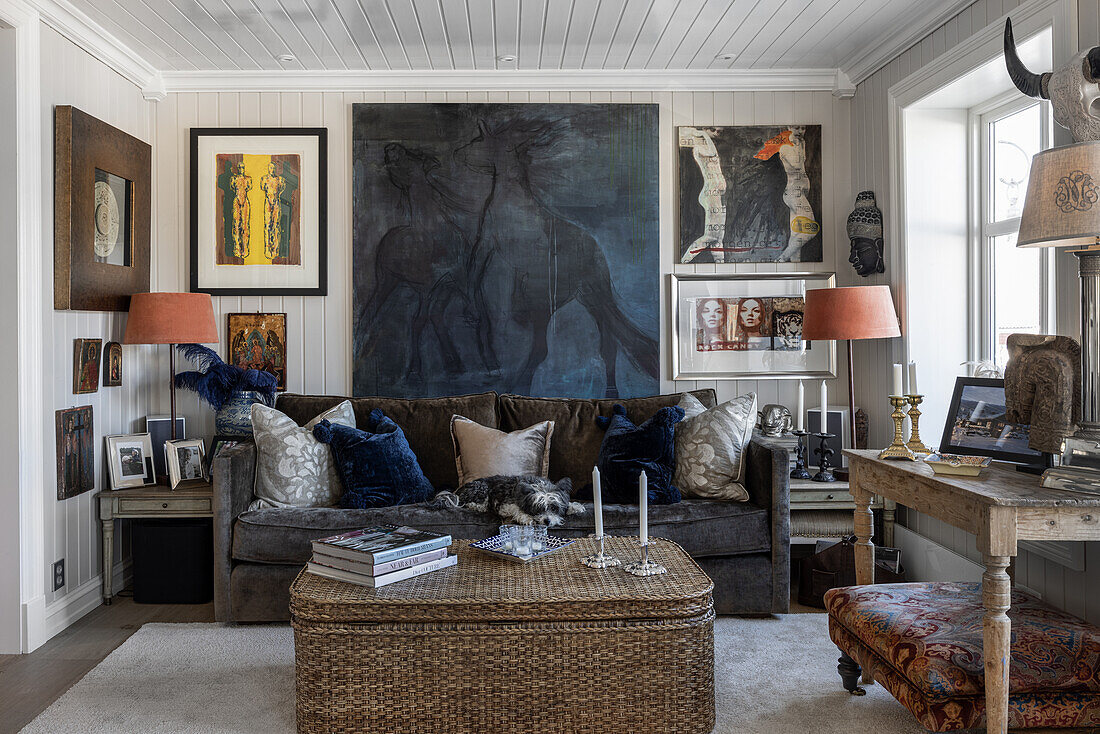 Wooden wall with picture gallery, upholstered sofa and chest as coffee table in vintage living room