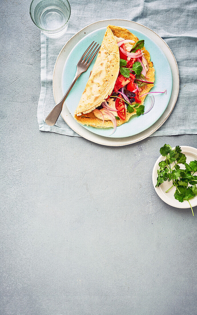Socca pancakes (chickpea flour pancakes) with hummus, tomatoes, and onions