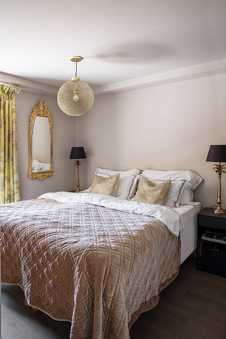 Doppelbett mit Tagesdecke vor Wand in beige