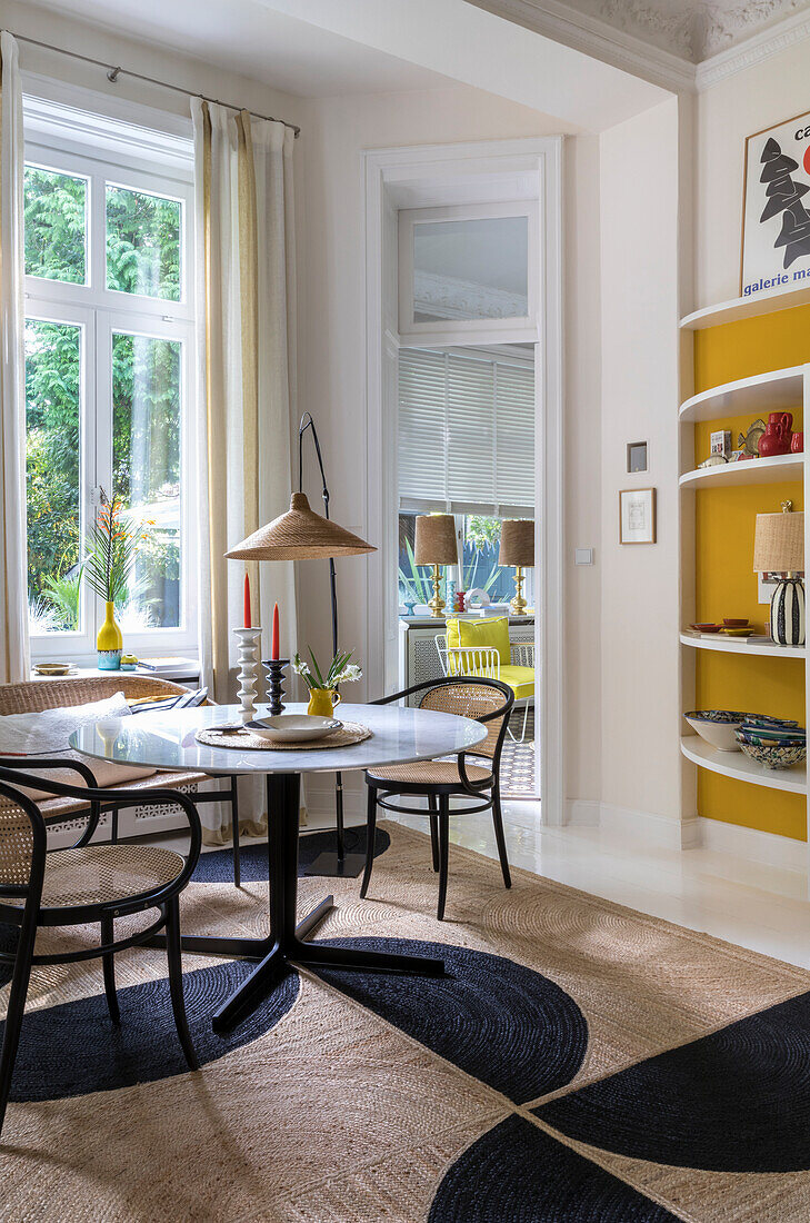 Round table with classic chairs in front of window in corner of room