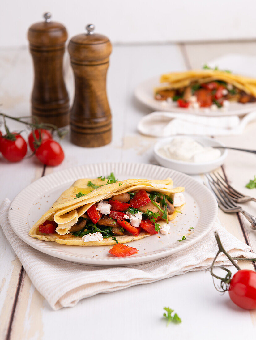 Spelt crêpes with rocket, peppers, mushrooms, tomatoes, and vegan cheese substitute