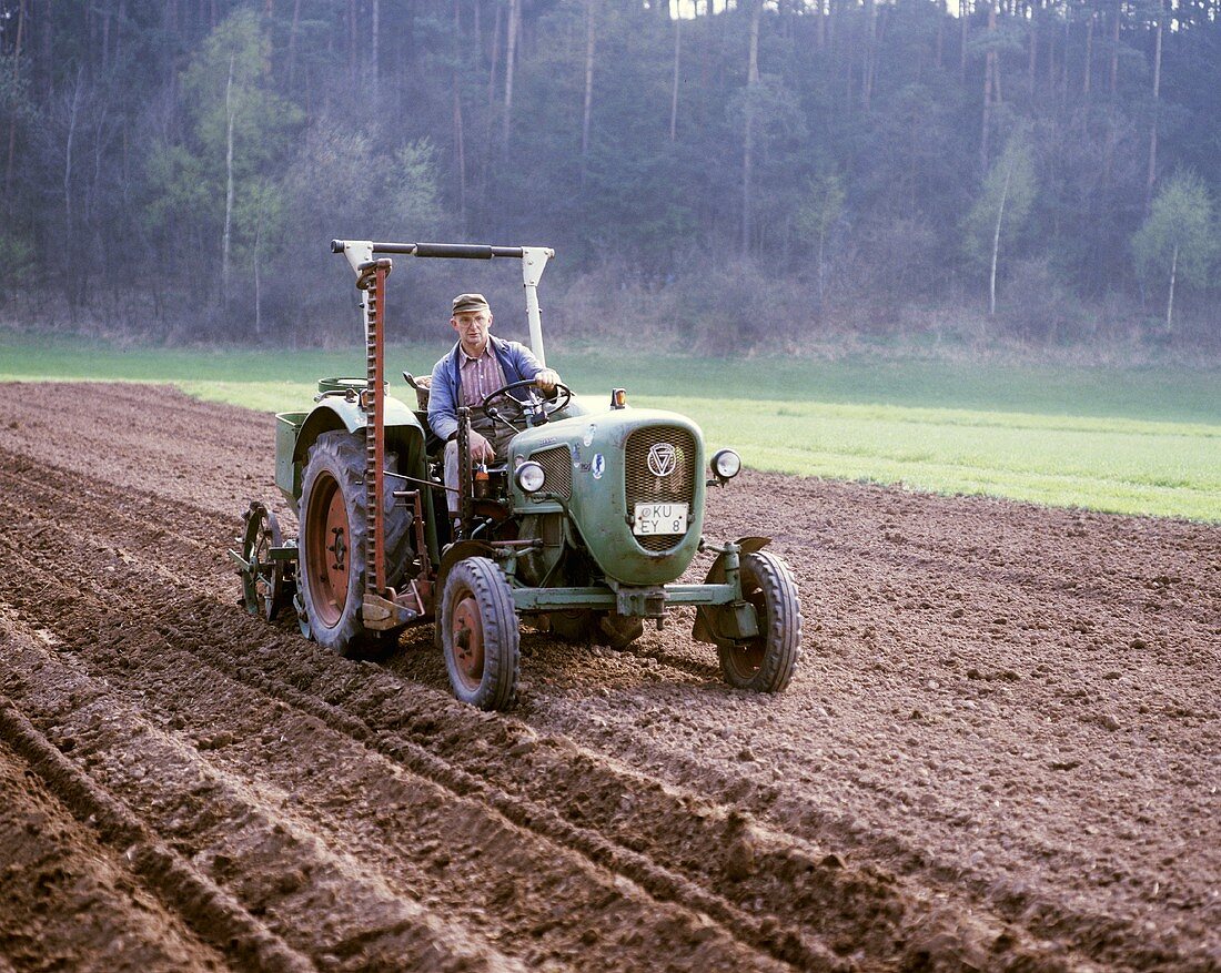Bauer bereitet Feld mit dem Traktor zur Kartoffelsaat vor