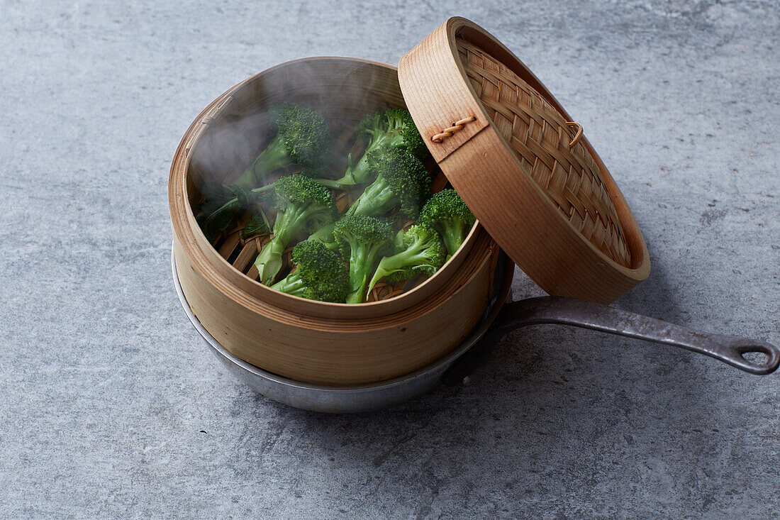 Broccoli florets being steamed in a bamboo basket
