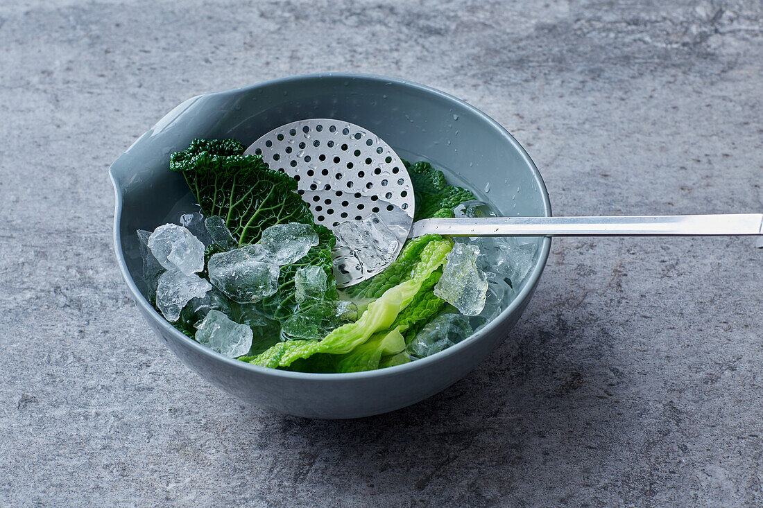Blanched savoy cabbage leaves being quenched with ice water