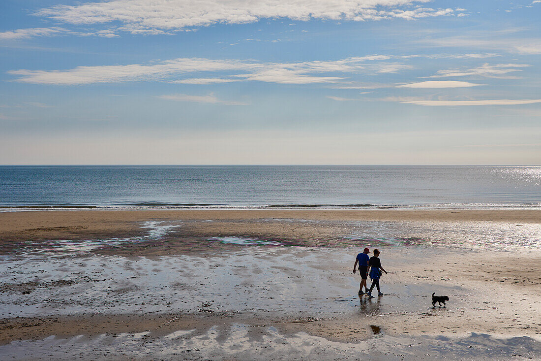 Pärchen geht mit Hund am North Bay Strand spazieren, Scarborough, Yorkshire, England, Vereinigtes Königreich, Europa