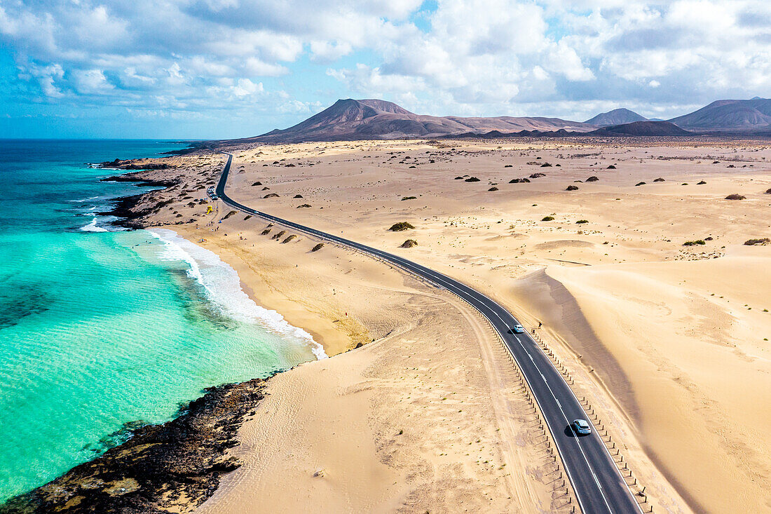 Luftaufnahme einer Straße durch die Wüste mit Blick auf das kristallklare Meer, Corralejo Naturpark, Fuerteventura, Kanarische Inseln, Spanien, Atlantik, Europa