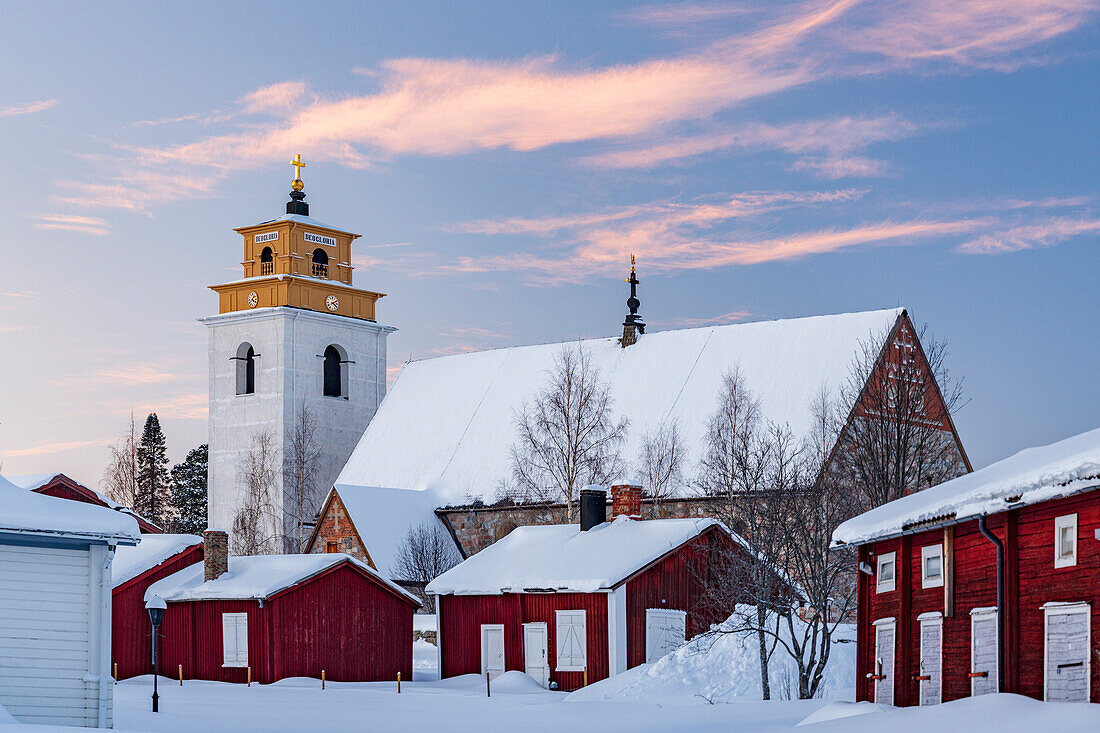 Alte Kirche und malerische, schneebedeckte Gebäude bei Sonnenuntergang in der Altstadt von Gammelstad, UNESCO-Weltkulturerbe, Lulea, Schweden, Skandinavien, Europa