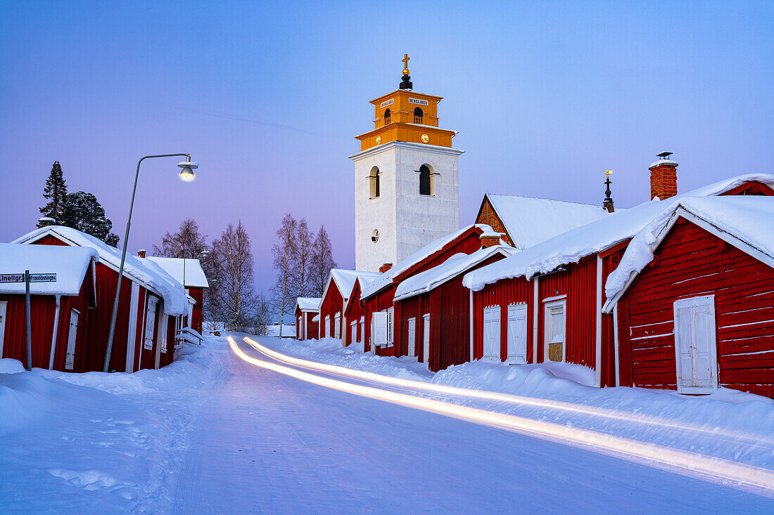 Car trails lights on the icy road crossing the medieval Gammelstad Church Town covered with snow, UNESCO World Heritage Site, Lulea, Sweden, Scandinavia, Europe