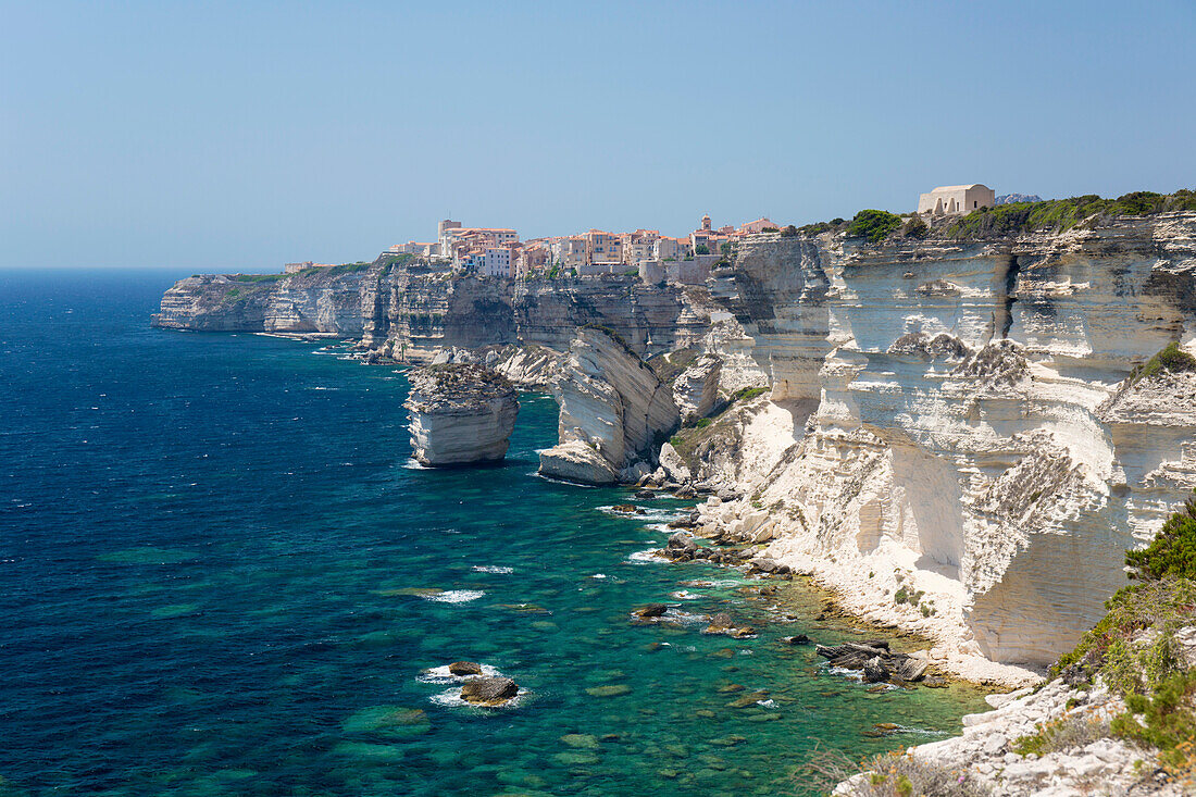 Blick über eine felsige Bucht entlang zerklüfteter Kalksteinklippen auf die ferne Zitadelle, Bonifacio, Corse-du-Sud, Korsika, Frankreich, Mittelmeer, Europa