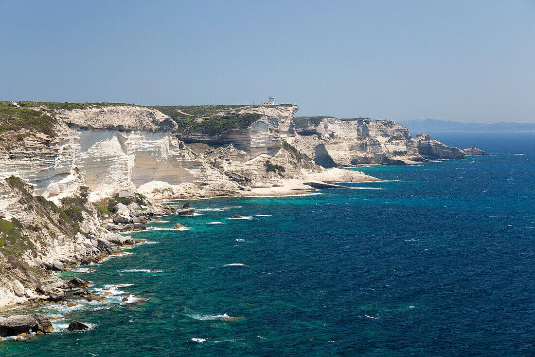 Blick entlang der zerklüfteten Kalksteinklippen auf Capo Pertusato und die ferne Küste Sardiniens, Bonifacio, Corse-du-Sud, Korsika, Frankreich, Mittelmeer, Europa