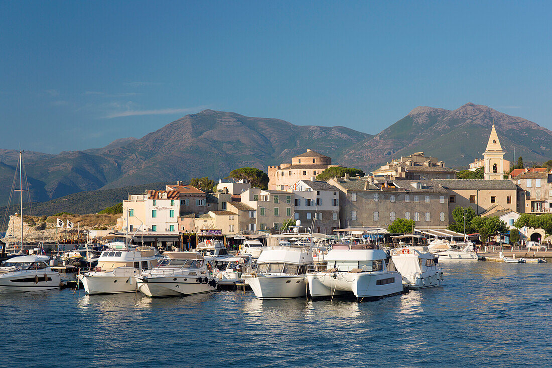 Blick über den Hafen auf die Stadt und die Zitadelle, dahinter die Hügel der Halbinsel Cap Corse, St-Florent, Haute-Corse, Korsika, Frankreich, Mittelmeer, Europa