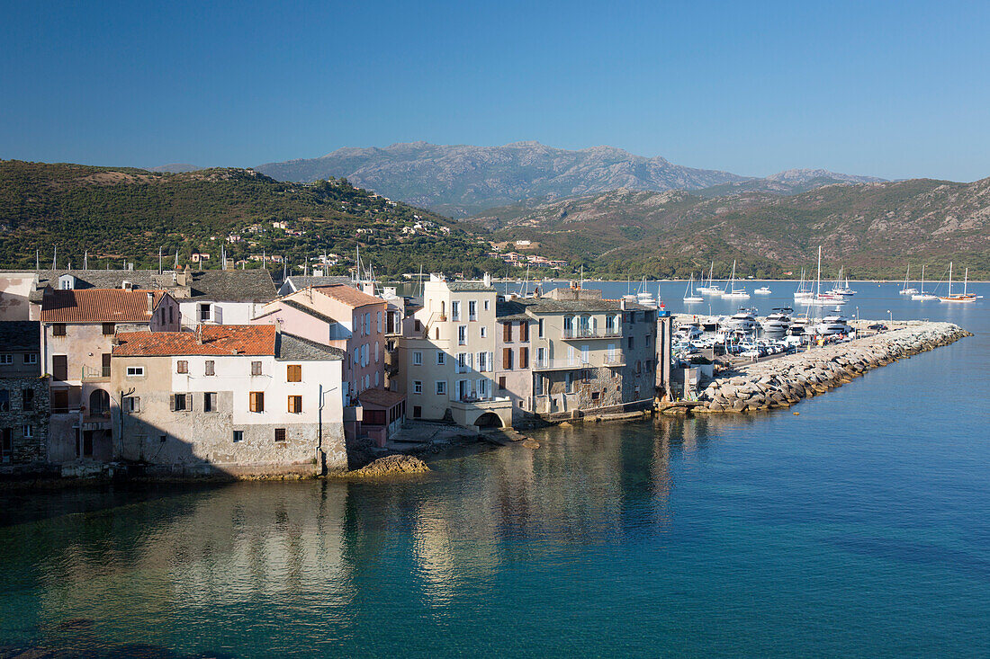 Blick über die Dächer von den Festungsmauern der Zitadelle, Häuser am Wasser spiegeln sich im ruhigen Meer, St-Florent, Haute-Corse, Korsika, Frankreich, Mittelmeer, Europa