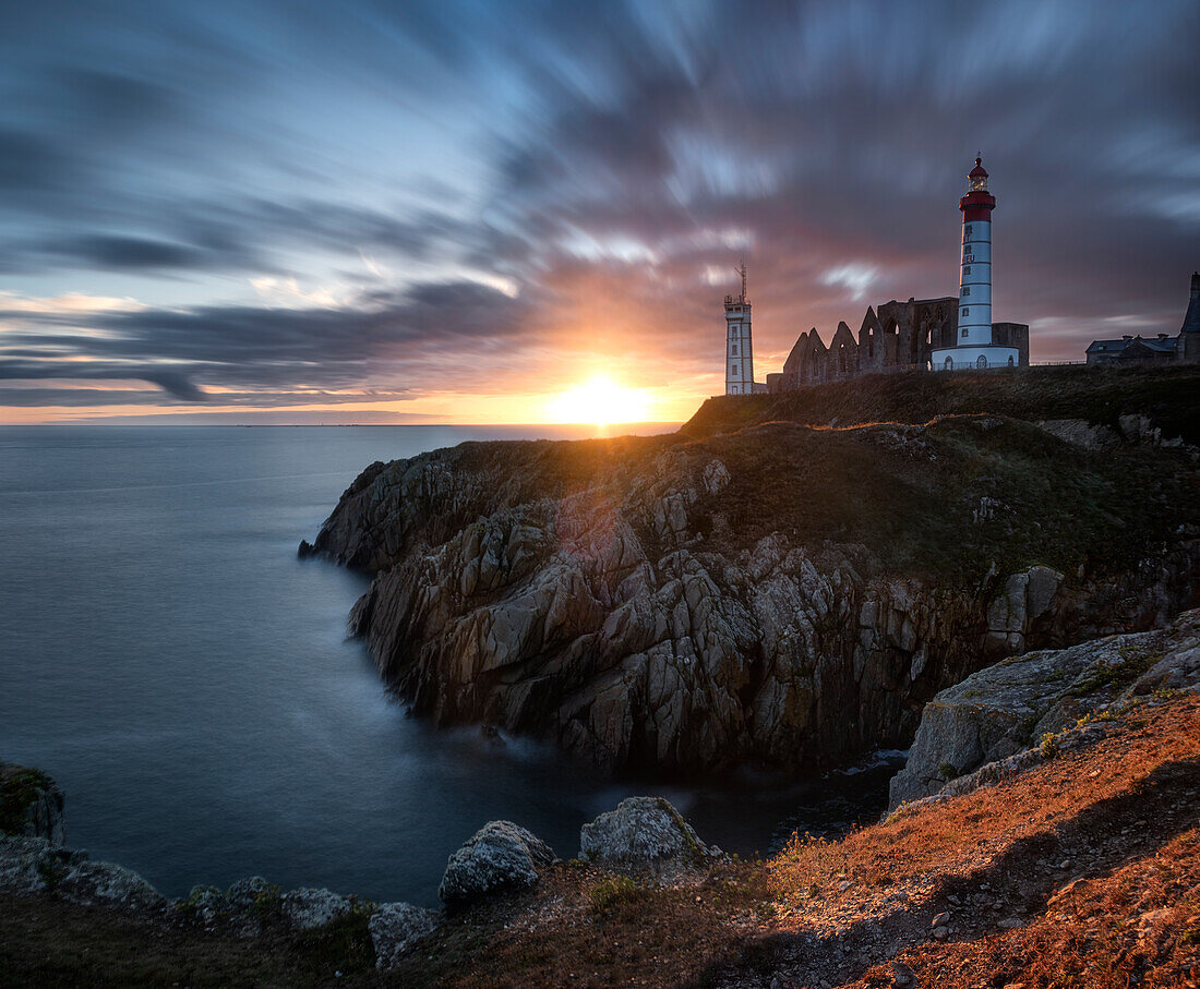 Langbelichtungspanorama eines Sonnenuntergangs mit farbigen Wolken am Leuchtturm Saint Mathieu, Finistere, Bretagne, Frankreich, Europa