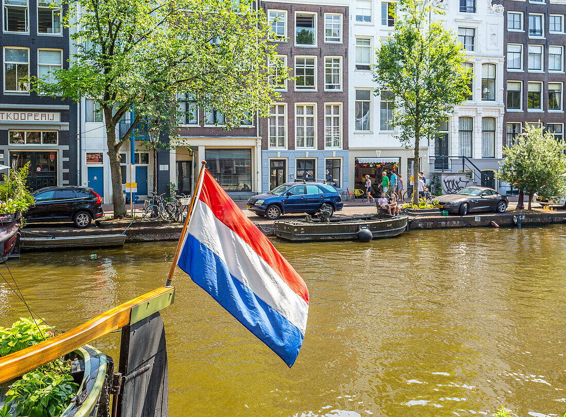 The Dutch flag flying from a houseboat on the Prinsengracht canal, Amsterdam, North Holland, The Netherlands, Europe