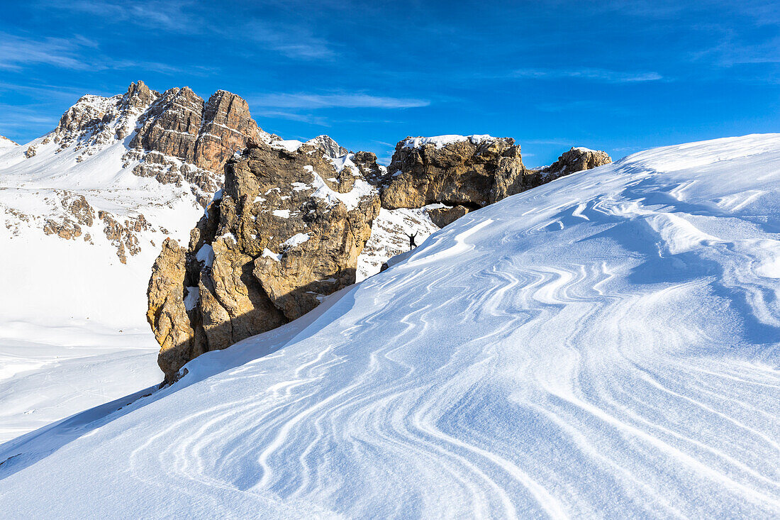 Eine Person und natürlicher Felsbogen mit vom Wind geformtem Schnee im Vordergrund, Julierpass, Graubünden, Schweiz, Europa