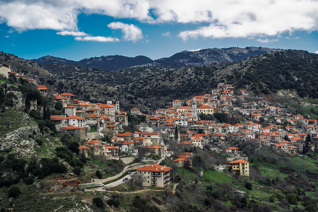 Griechisches Dorf mit Bergpanorama und traditionellen niedrigen Häusern mit roten Dachziegeln in Dimitsana, Arkadien, Peloponnes, Griechenland, Europa