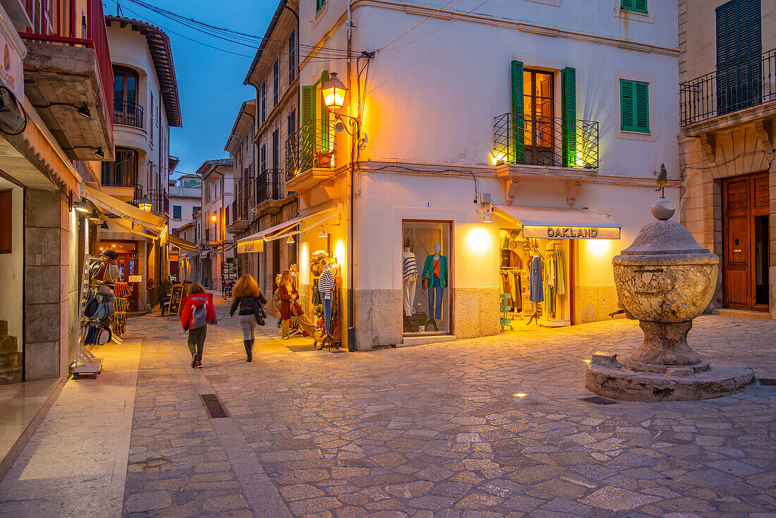 Blick auf Geschäfte in einer engen Straße in der Altstadt von Pollenca in der Abenddämmerung, Pollenca, Mallorca, Balearen, Spanien, Mittelmeer, Europa