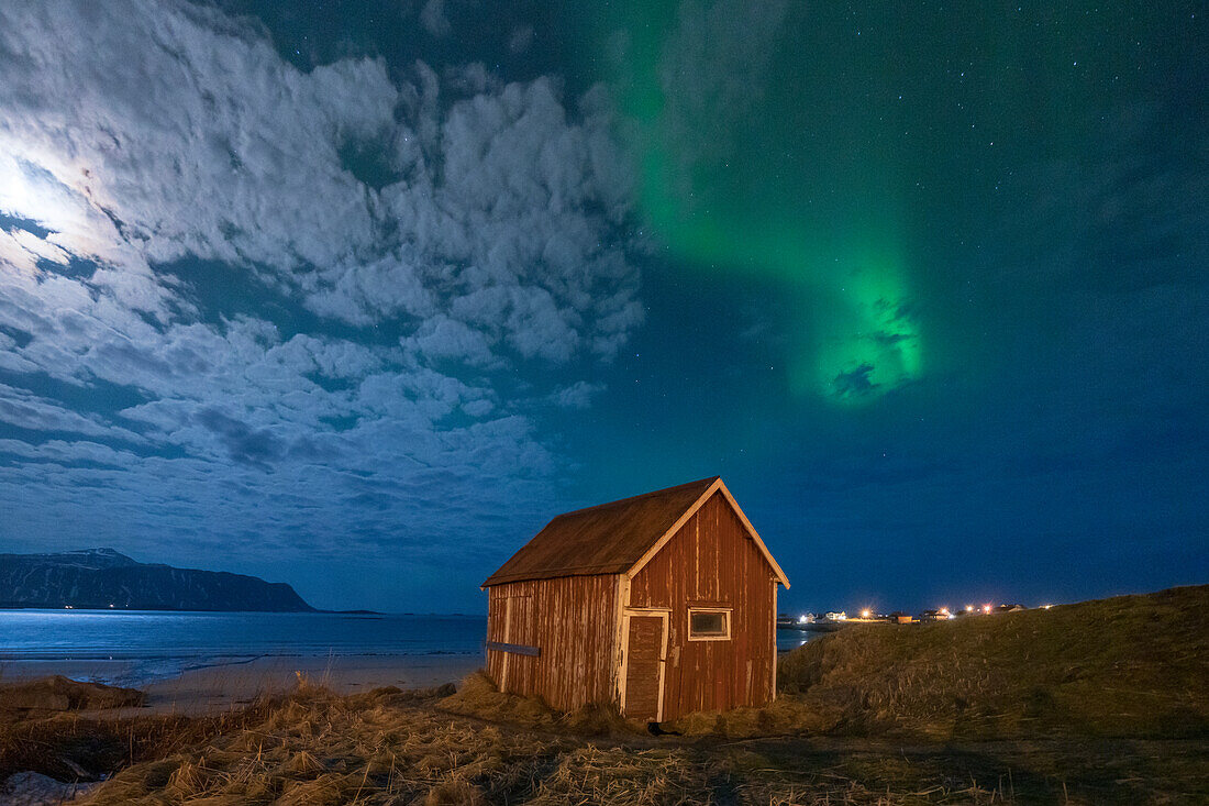 Rote Hütte unter dem hellen Nachthimmel, beleuchtet von Mond und Aurora Borealis (Nordlicht), Ramberg, Nordland, Lofoten, Norwegen, Skandinavien, Europa