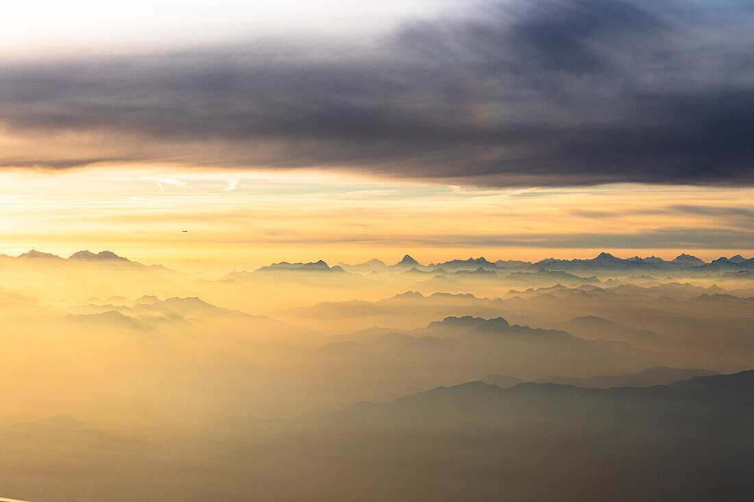 Flug über die majestätischen Schweizer Alpen in einem Meer von Wolken bei Sonnenuntergang, Schweiz, Europa