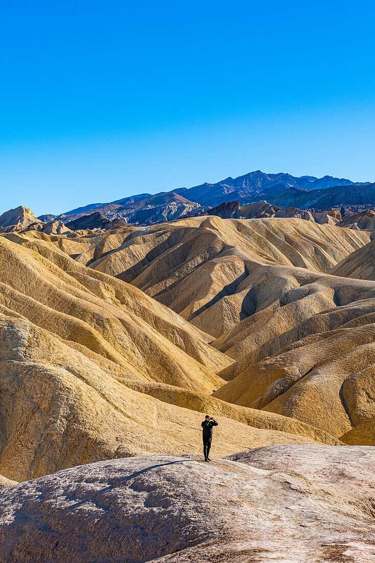 Hiker in the colourful sandstone formations, Zabriskie Point, Death Valley, California, United States of America, North America
