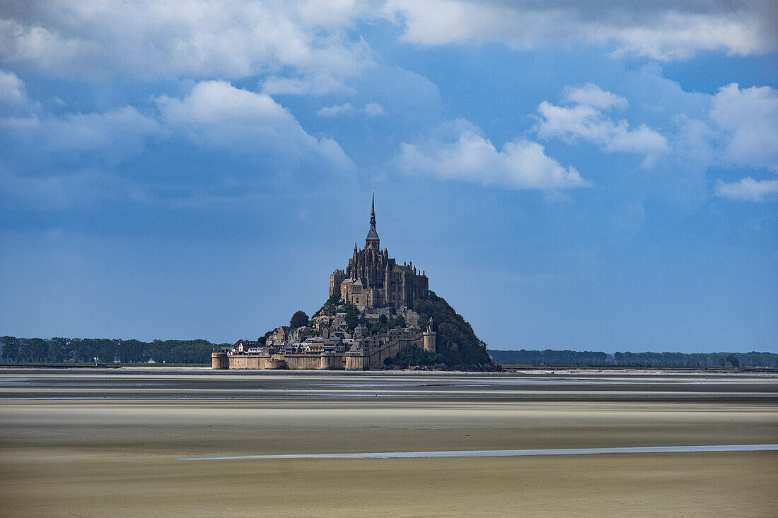 Le Mont Saint Michel, UNESCO World Heritage Site, at low tide on a sunny day with some white clouds, Normandy, France, Europe