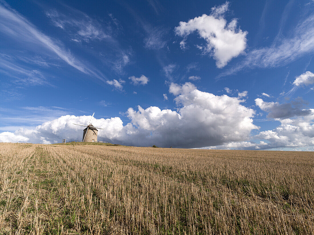 Windmühle in einem abgeernteten Feld mit blauem Himmel und weißen Wolken, Normandie, Frankreich, Europa