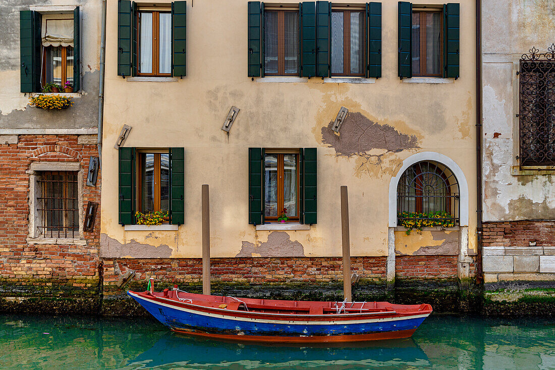 An empty red and blue boat moored in Rio della Misericordia, Venice, UNESCO World Heritage Site, Veneto, Italy, Europe