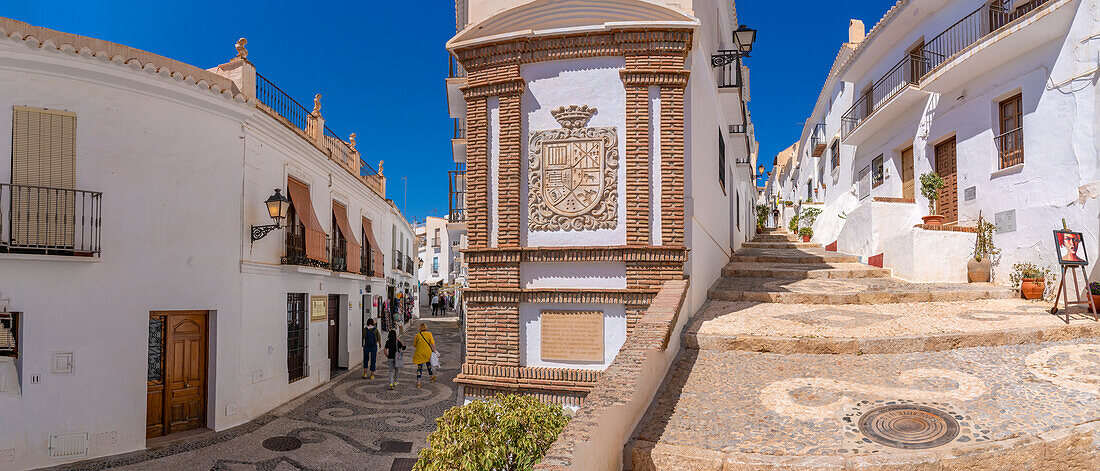 Blick auf weiß getünchte Häuser und Einkäufer in einer schmalen Straße, Frigiliana, Provinz Malaga, Andalusien, Spanien, Mittelmeer, Europa