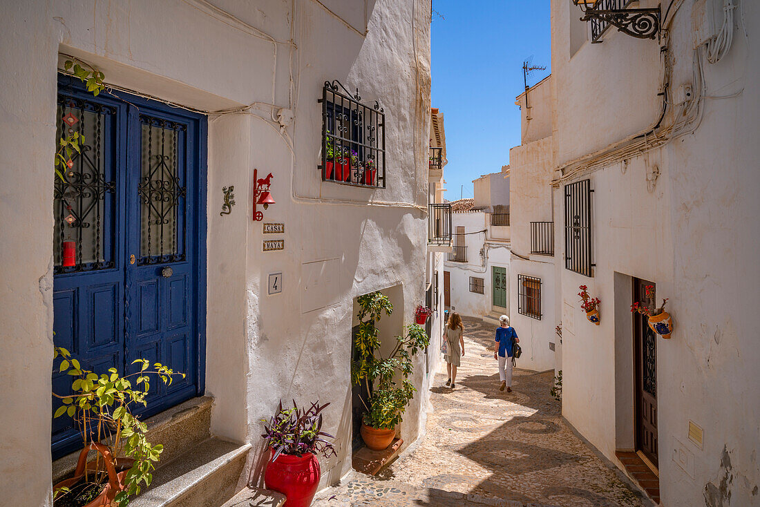 View of ladies walking through narrow street of whitewashed houses, Frigiliana, Malaga Province, Andalucia, Spain, Mediterranean, Europe