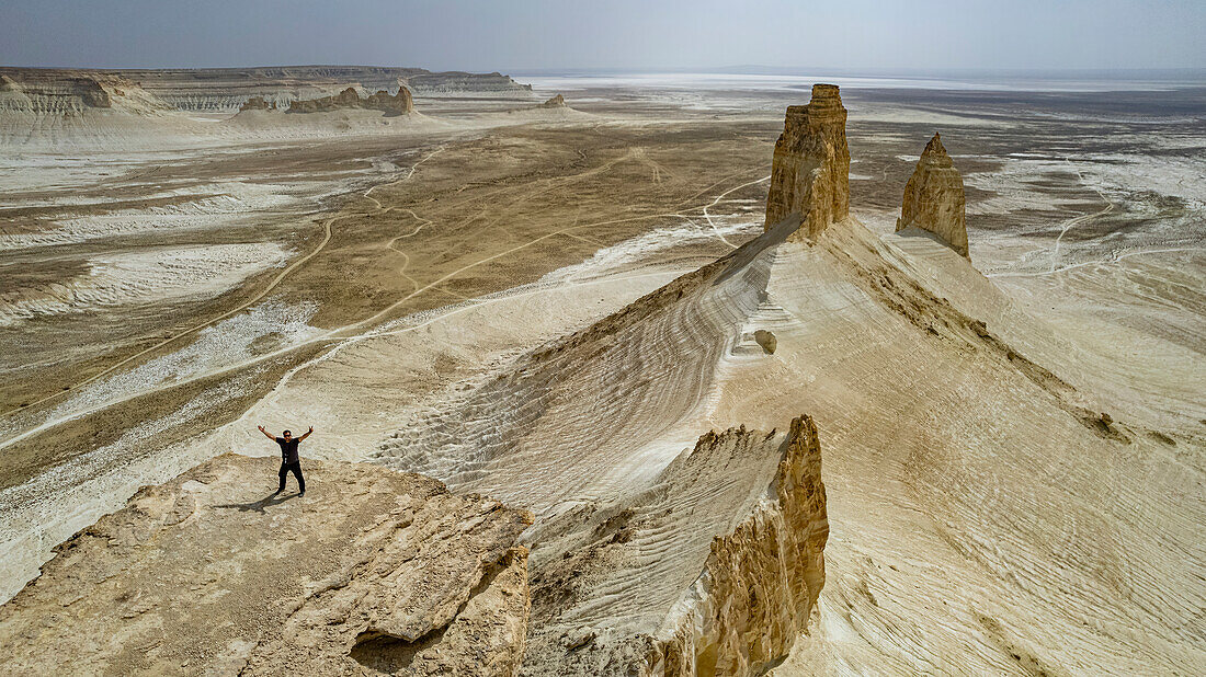 Luftaufnahme eines Mannes, der auf einem Felsen steht, Bozzhira-Schlucht, Ustyurt-Hochebene, Mangystau, Kasachstan, Zentralasien, Asien