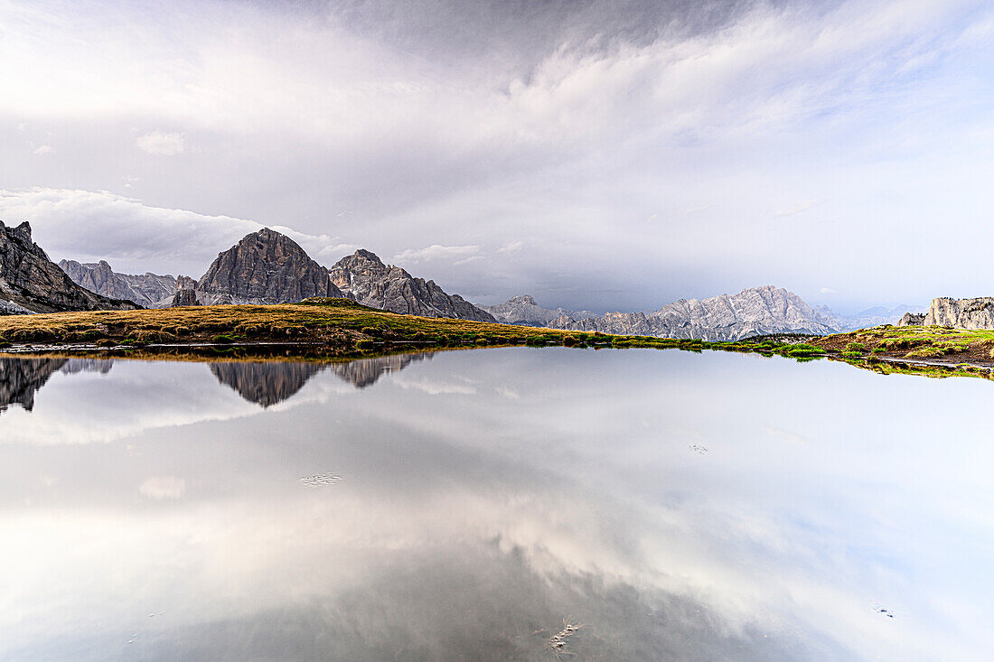 Bright sky at dawn over Monte Cristallo and Tofane mountains mirrored in water, Giau Pass, Dolomites, Veneto, Italy, Europe