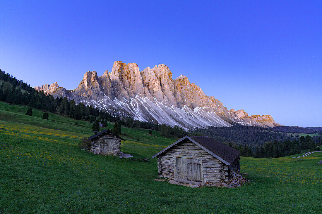 Sonnenaufgang über der Geislergruppe und den Berghütten im Frühling, Gampen Alm, Funes Tal, Dolomiten, Südtirol, Italien, Europa