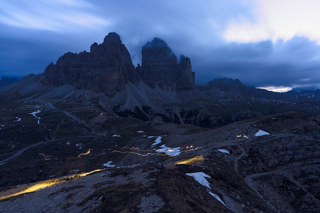 Clouds at dusk in the foggy sky over the majestic rocks of Tre Cime di Lavaredo, Dolomites, South Tyrol, Italy, Europe