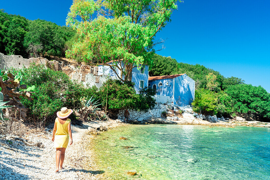 Frau spaziert auf weißen Kieselsteinen an einem von Bäumen umgebenen Strand, Porto Atheras, Kefalonia, Ionische Inseln, Griechische Inseln, Griechenland, Europa