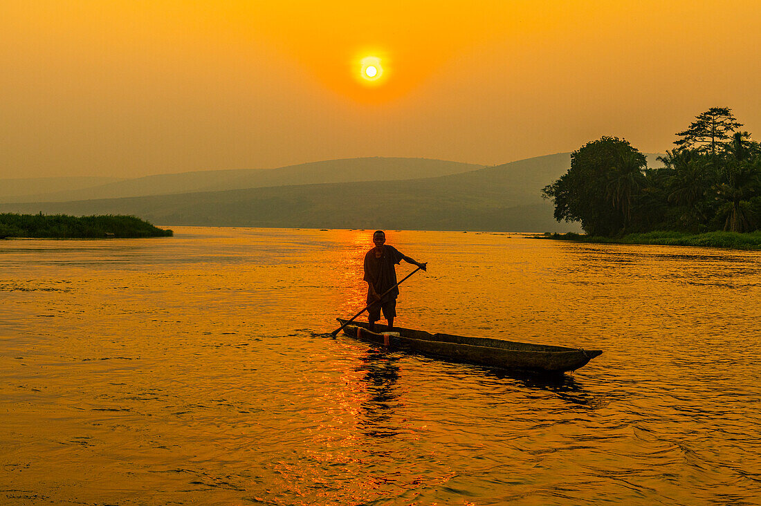 Mann auf seinem Einbaum bei Sonnenuntergang auf dem Kongo-Fluss, Demokratische Republik Kongo, Afrika