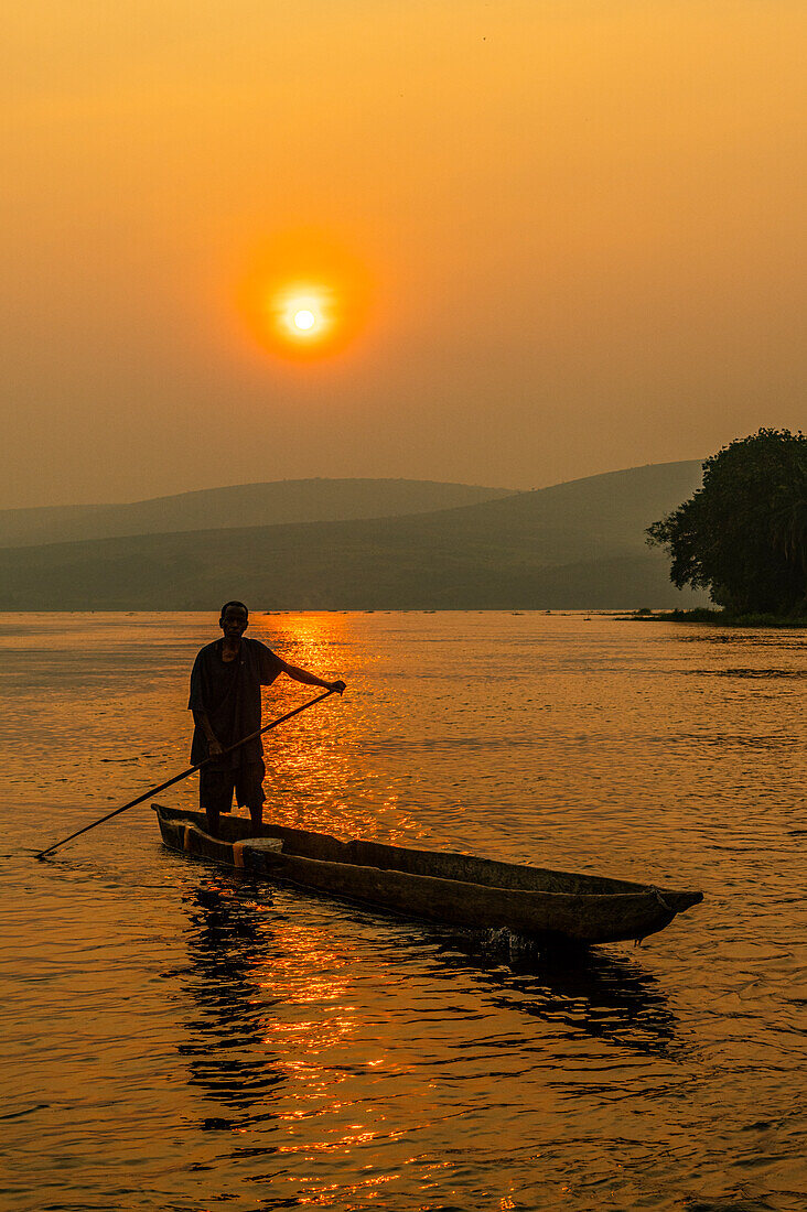 Mann auf seinem Einbaum bei Sonnenuntergang auf dem Kongo-Fluss, Demokratische Republik Kongo, Afrika
