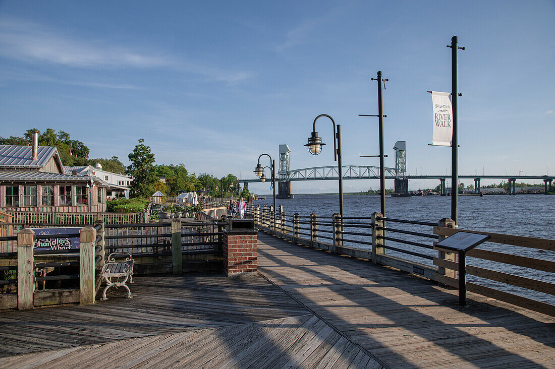 Sonnenuntergang auf dem Riverwalk entlang des Cape Fear River mit Flussbrücke im Hintergrund, Wilmington, North Carolina, Vereinigte Staaten von Amerika, Nordamerika