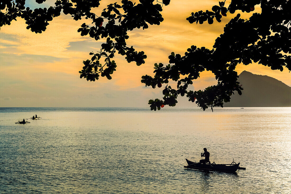 Fischer paddeln mit Auslegerkanus bei Sonnenuntergang am Strand von Kalea, Kalea, Siau-Insel, Sangihe-Archipel, Nordsulawesi, Indonesien, Südostasien, Asien