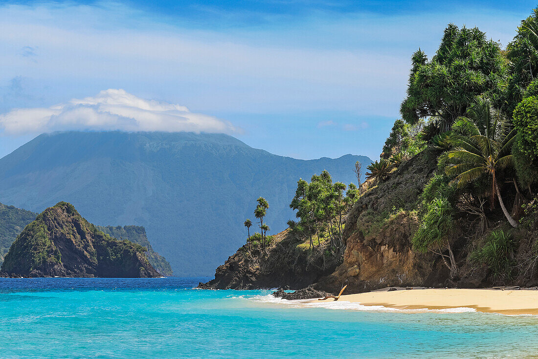 Turquoise sea at Mahoro Island and cloudy Karangetang volcano beyond, Mahoro, Siau, Sangihe Archipelago, North Sulawesi, Indonesia, Southeast Asia, Asia