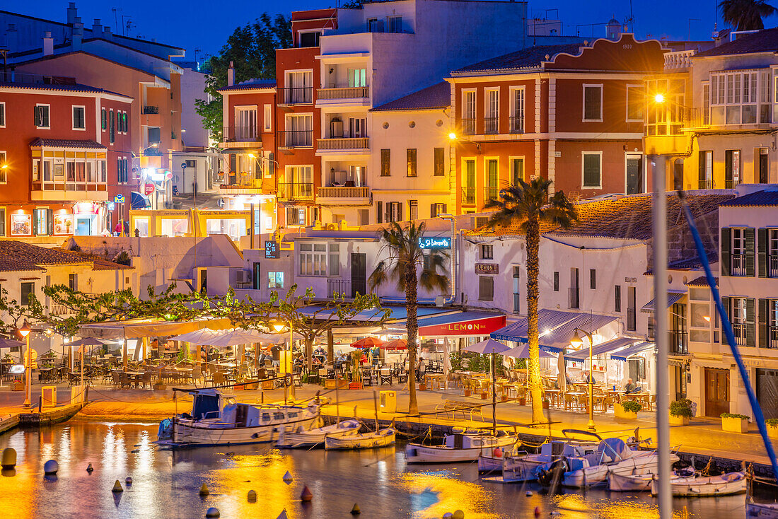 Blick auf Cafés, Restaurants und Boote im Hafen in der Abenddämmerung, Cales Fonts, Es Castell, Menorca, Balearische Inseln, Spanien, Mittelmeer, Europa