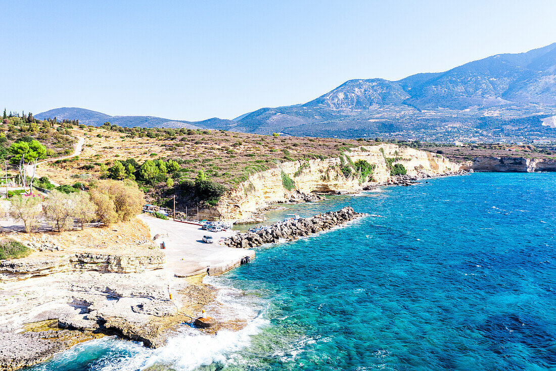 Die Wellen des türkisfarbenen Meeres brechen an den Felsen des kleinen Hafens von Pessada, Luftaufnahme, Kefalonia, Ionische Inseln, Griechische Inseln, Griechenland, Europa