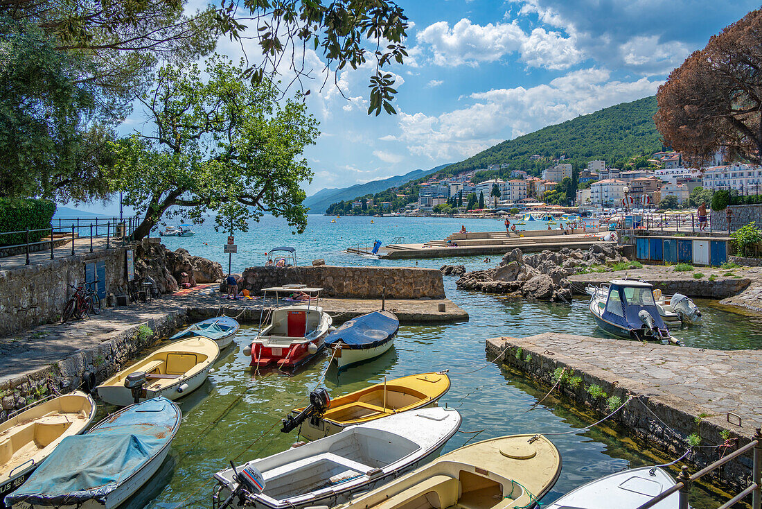 Blick auf eine felsige Bucht und Boote mit der Stadt Opatija im Hintergrund, Opatija, Kvarner Bucht, Kroatien, Europa