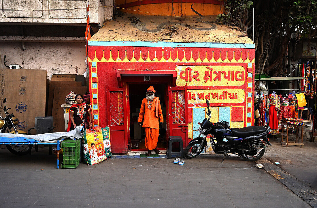 In heiliges Orange gekleideter Hindu-Pundit in einem winzigen Hindu-Tempel in der Nähe des Gomati Ghat, Dwarka, Gujarat, Indien, Asien