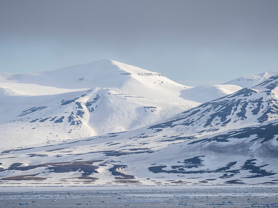 Schneebedeckte Berge und kahle Felsen an der Küste von Spitzbergen, Storfjorden, Svalbard, Norwegen, Europa