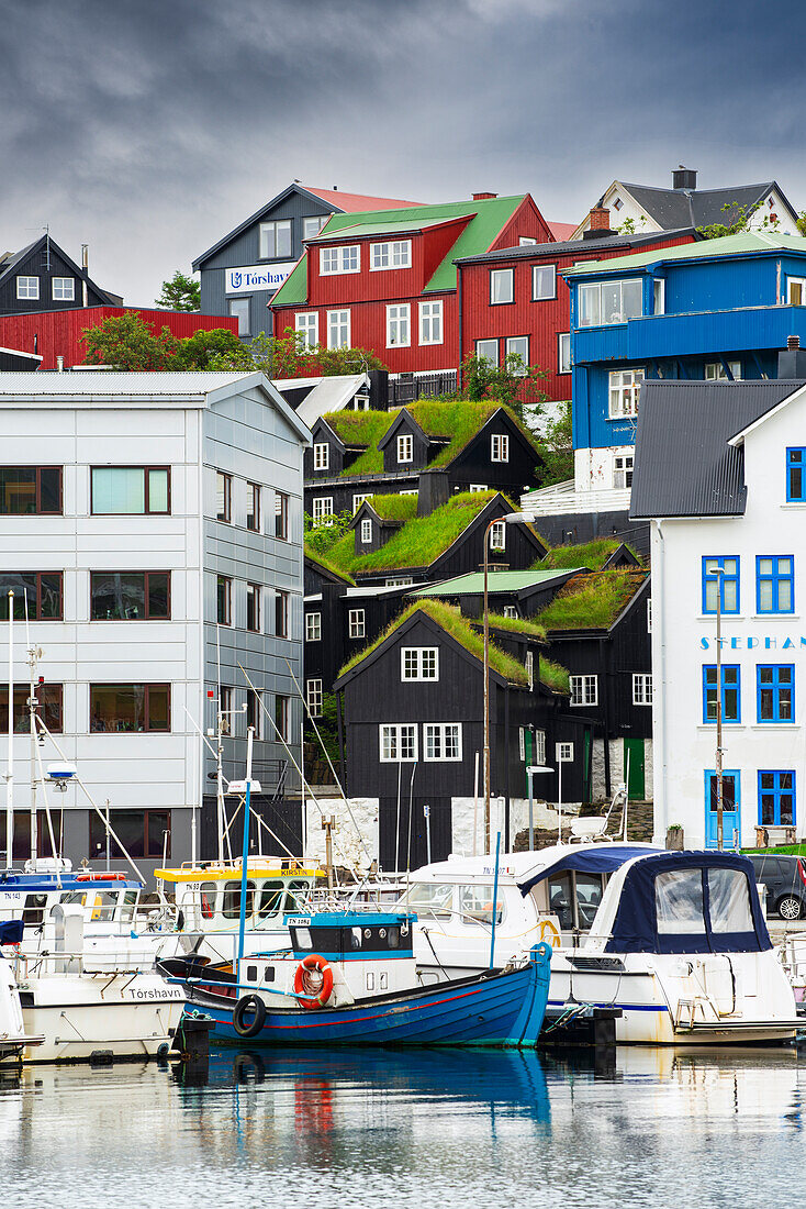 Old grass roof houses among new buildings and boats in the harbour of Torshavn, Streymoy island, Faroe Islands, Denmark, Europe